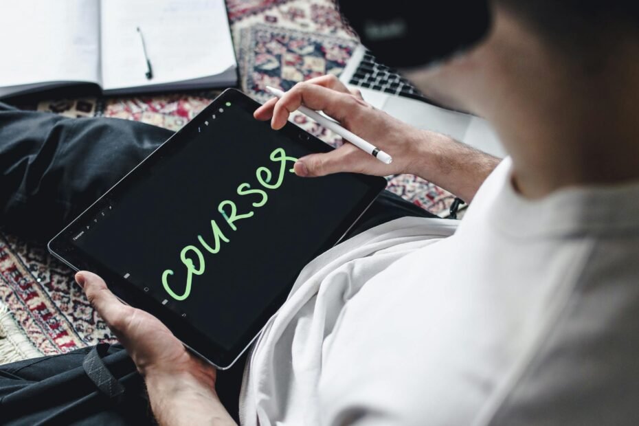 Individual wearing headphones using a digital tablet for online learning. Indoors setting.